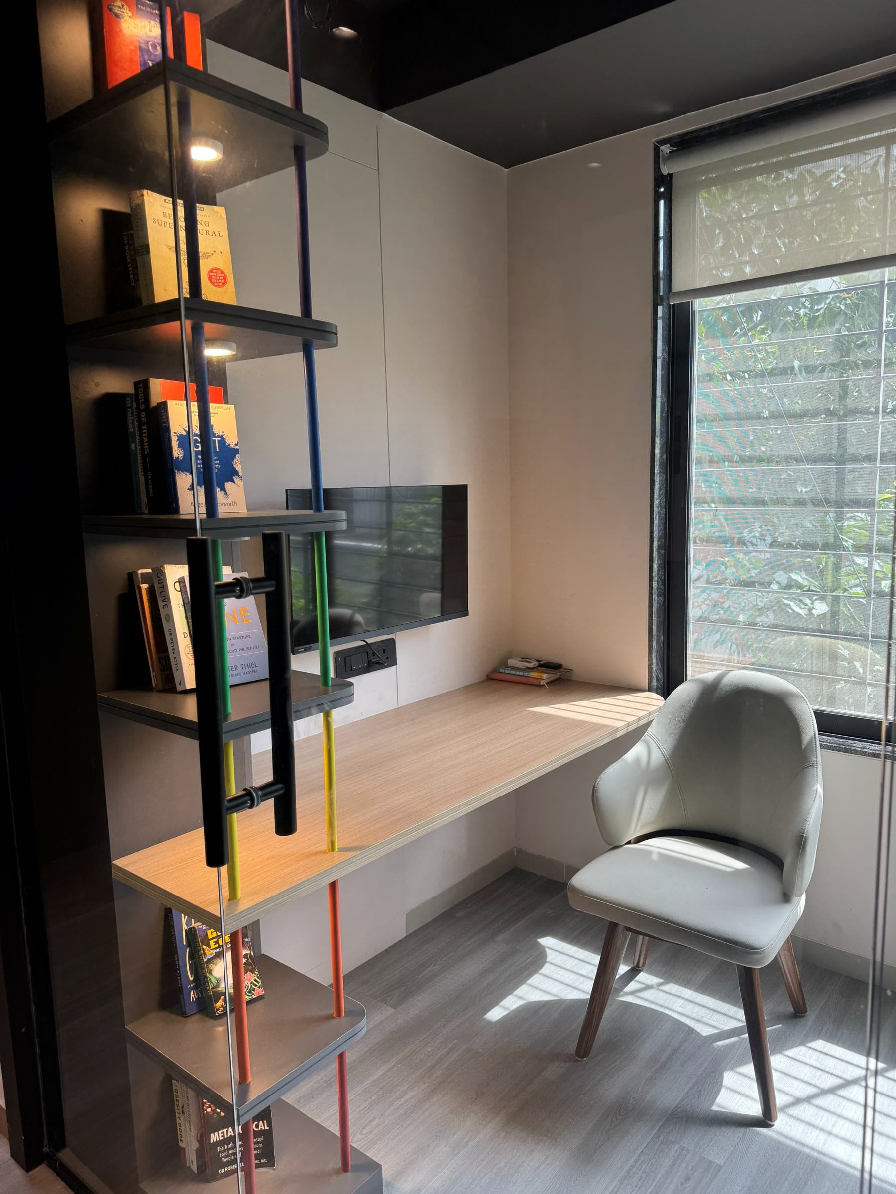 A quiet desk space at Like Human, with bookshelves, a soft chair and a window onto greenery
